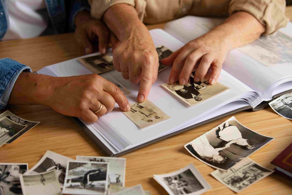 Hands sorting through old family photographs while researching Canadian ancestry